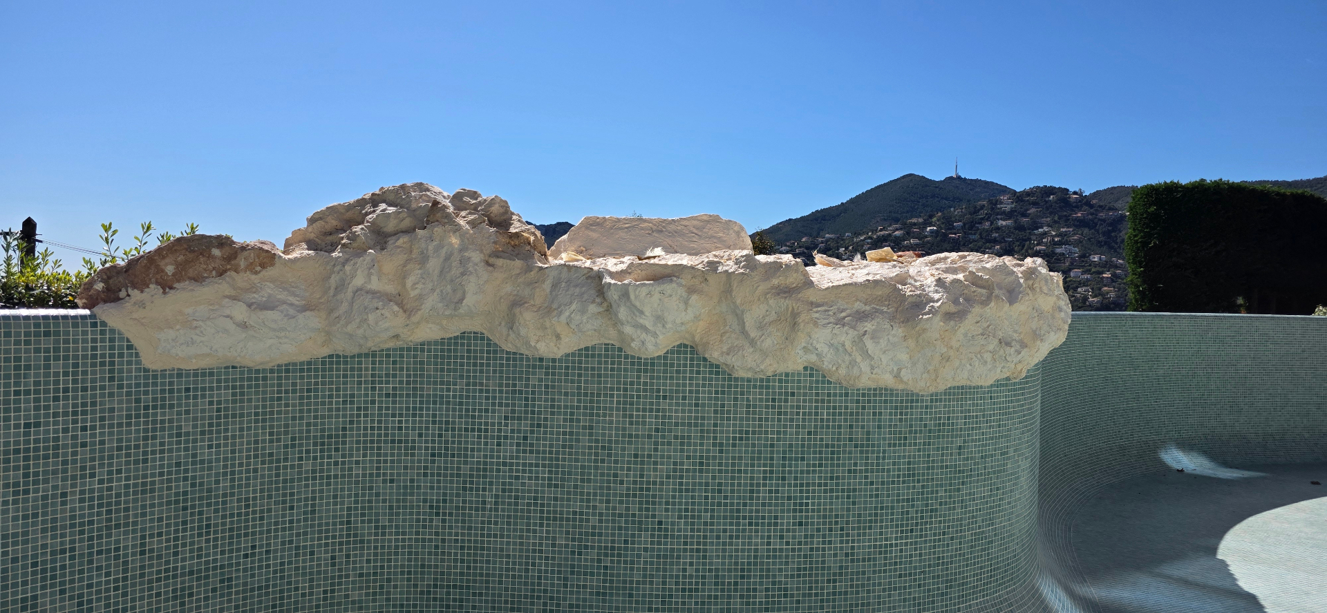 Rocas artificiales de piscina de poliéster en proceso de instalación – decorado rocoso a medida en el borde de una piscina de mosaico, Costa Azul