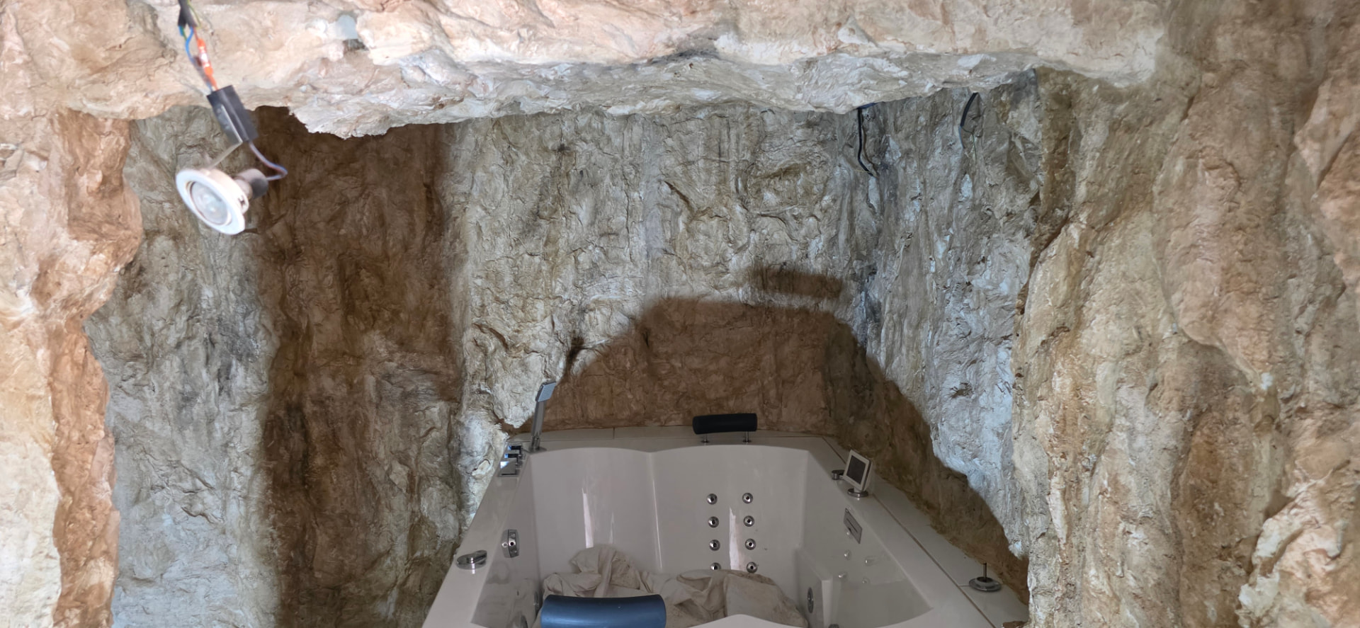 Techo de roca artificial de poliéster e iluminación empotrada sobre la bañera de hidromasaje – decoración inmersiva estilo gruta natural