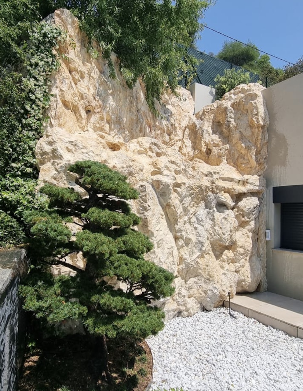 Mur béton transformé en décor roche naturelle par un habillage en faux rocher polyester patiné